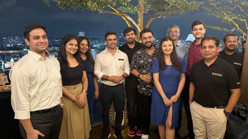 Alumni networking at an evening rooftop event with city skyline